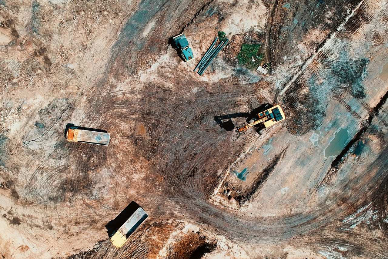 Luchtfoto van grondwerken met een graafmachine en vrachtwagens
