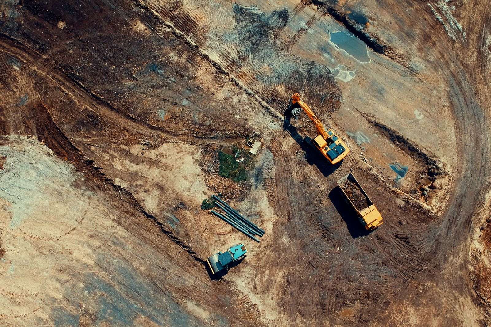 Luchtfoto van grondwerken met een graafmachine en een kiepwagen